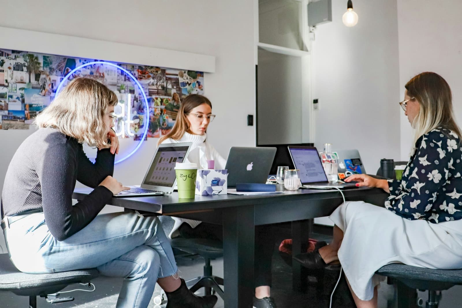 A small team working on laptops around a shared table in their office